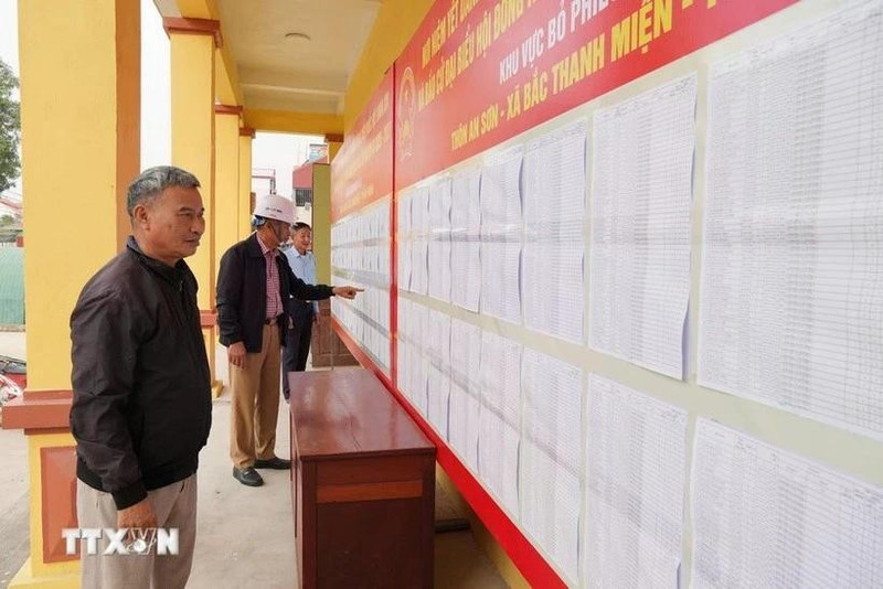 Voters review the lists of candidates and their brief biographies. (Photo: VNA)