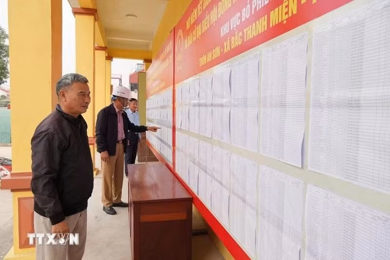 Voters review the lists of candidates and their brief biographies. (Photo: VNA)
