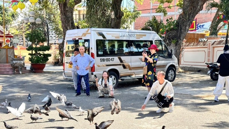 Visitors at Thang Tam communal house call doves to the courtyard.