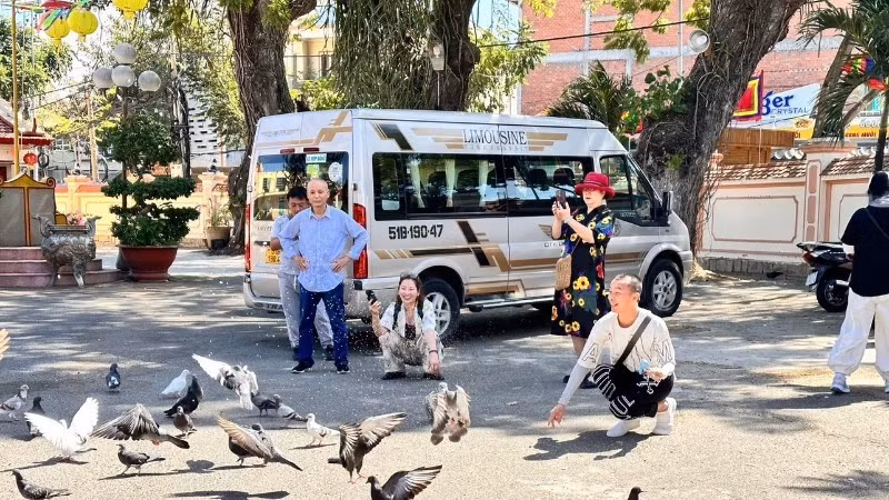 Visitors at Thang Tam communal house call doves to the courtyard.