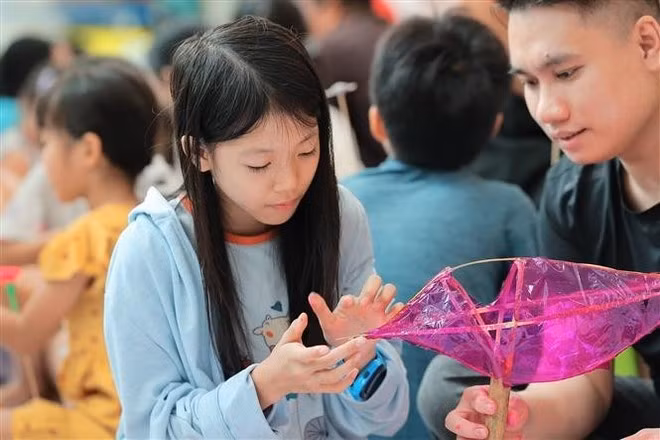 Children experience making fish-shaped lanterns. (Photo: VNA)
