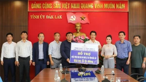 The working delegation presents a symbolic cheque for the relief funding to representatives of Dak Lak Province.