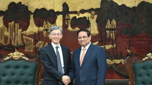 Prime Minister Pham Minh Chinh (R) welcomes Deputy Managing Director of the International Monetary Fund Kenji Okamura. (Photo: NDO)