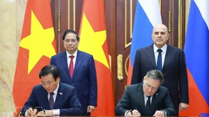 Vietnamese PM Pham Minh Chinh (standing, left) and his Russian counterpart Mikhail Mishustin (standing, right) witness the signing of the agreement between the two governments on cooperation in building a nuclear power plant on the territory of Viet Nam. (Photo: VNA)