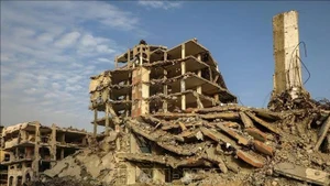 People walking alongside buildings destroyed by conflict in Gaza city (Photo: Xinhua/VNA)