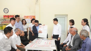 Le Quoc Minh, Editor-in-Chief of Nhan Dan Newspaper, presents the special supplement on the Draft Documents for the 14th National Party Congress to residents at the post office in Da Trach Commune, Hung Yen Province. (Photo: The Dai)