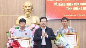Chairman of the Quang Ngai provincial People's Committee Nguyen Hoang Giang (centre) presents the State President's Bravery Order to two citizens of Ly Son special zone on December 15. (Photo: NDO)