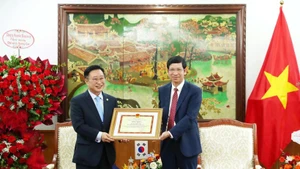 Deputy Minister of Culture, Sports and Tourism Ho An Phong presents a certificate of merit to Ly Xuong Can for his contributions to promoting tourism cooperation between the two countries. (Photo: VNA)