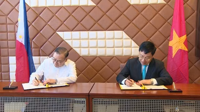 Vietnamese Deputy PM and FM Pham Binh Minh (R) and Philippine Foreign Secretary Teodoro Lopez Locsin (L) sign the minutes of the ninth meeting of the Vietnam - Philippines Joint Commission for Bilateral Cooperation in Manila on March 6. (Photo: MOFA)