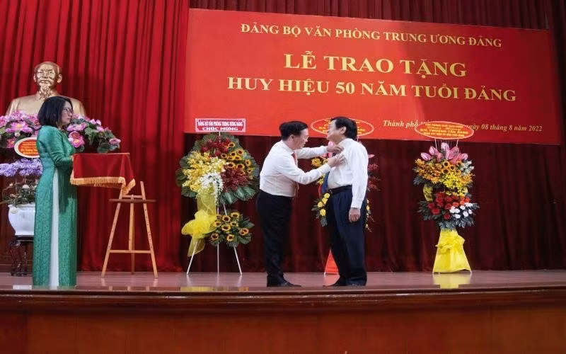 Politburo member Vo Van Thuong grants the 50-year Party membership insignia to former President Truong Tan Sang.