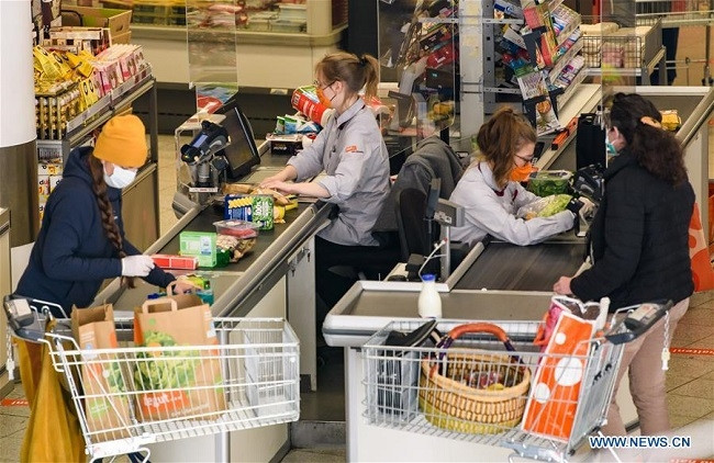 Cashiers and customers wearing face masks are seen at a supermarket in Jena, Germany, April 6, 2020. The eastern German city of Jena became the first in the country to make wearing a protective face mask mandatory in public areas, such as shops, on public transportation and in buildings with public access during the COVID-19 pandemic. (Photo: Xinhua)