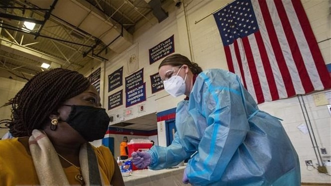 A medical worker injecting Moderna's COVID-19 vaccine to people in Central Falls, Rhode Island, the US. 