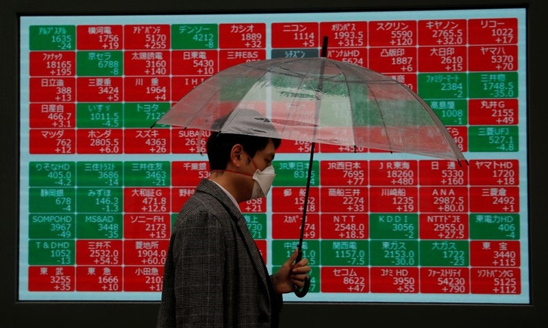 A visitor wearing protective face mask, following an outbreak of the coronavirus, walks past in front of a stock quotation board outside a brokerage in Tokyo, Japan March 2, 2020. (Photo: Reuters)