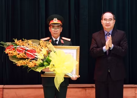 Politburo member Nguyen Thien Nhan (right) presents the accolade to late professor Buu’s relative (Photo: qdnd.vn)