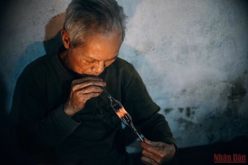 At his glass factory, Mr. Ho Van Gung (72 years old), who has been with the glass industry for more than 40 years, is producing hot batches of kerosene lamps.