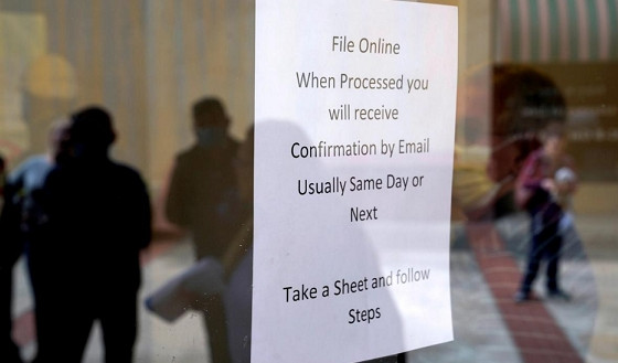 People who lost their jobs are reflected in the door of an Arkansas Workforce Centre as they wait in line to file for unemployment following an outbreak of COVID-19, in Fort Smith, Arkansas, US, April 6, 2020. (Photo: Reuters)