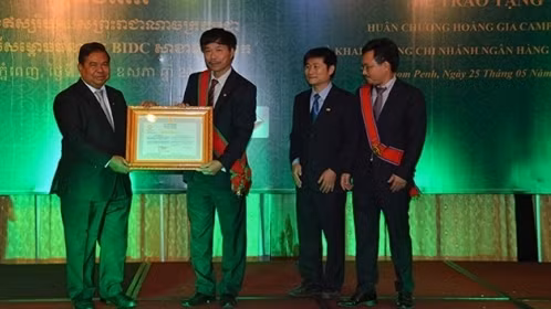 Governor of the National Bank of Cambodia Chea Chanto (left) grants the certificate of establishment of the Toul Kork-branch bank to a representative from BIDC
