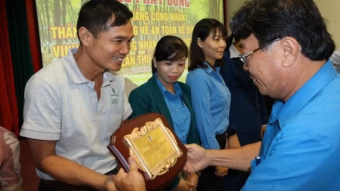 Phan Manh Hung, President of Vietnam Rubber Trade Union (far right) presents the title of outstanding rubber workers to labourers under the rubber industry. (Photo: congdoancaosu.vn)