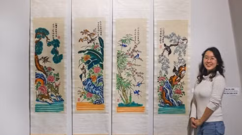 Designer Trinh Thu Trang standing next to Hang Trong folk paintings (Photo: giaoducthoidai.vn)