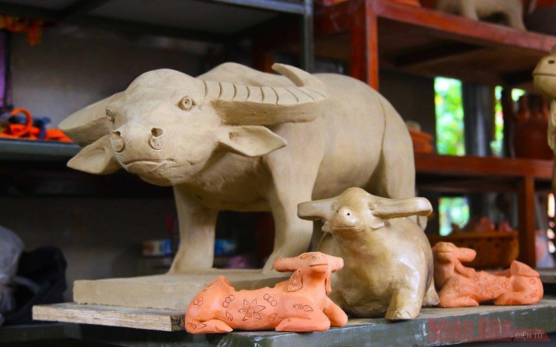 Clay buffalos are featured in various postures of standing, lying, and eating grass.