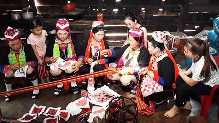 Members of Quang Ha Village’s embroidery group give instructions to local Red Dao girls and women (Photo: NDO/Thuy Vu)