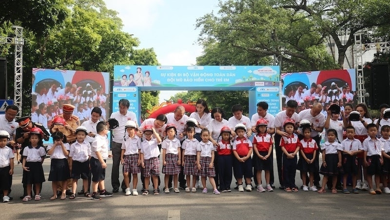 Leaders present crash helmets to schoolchildren. (Photo: NDO/Bong Mai)