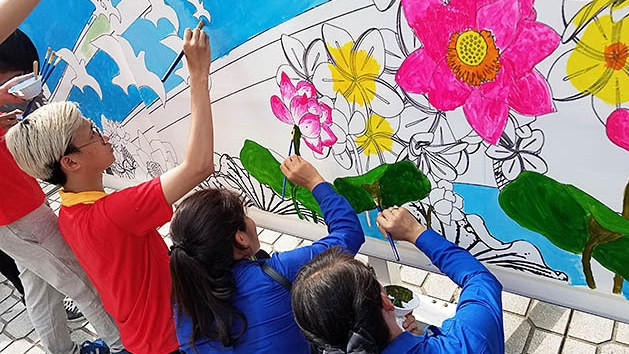 The painting is completed as a joint effort from a total of 550 Vietnamese youngsters (in red) and their Lao friends (in blue).