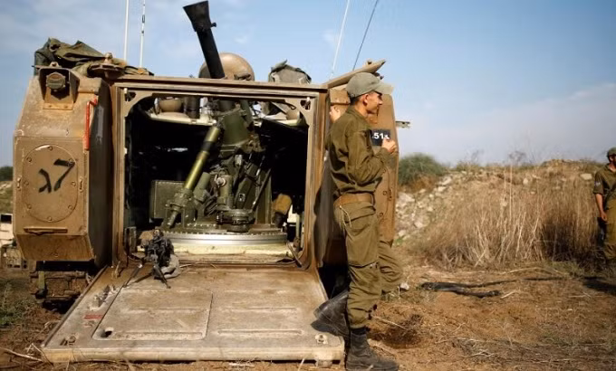An Israeli soldier stands next to an armoured personnel carriers (APC) in a field in southern Israel, near the border with Gaza November 13, 2018. (Reuters)