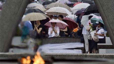 People pray for the atomic bomb victims in a rain at the Hiroshima Peace Memorial Park in Hiroshima.