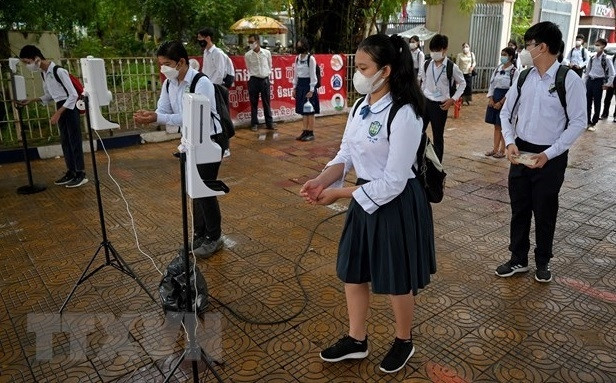 Students wash their hands and get their temperatures checked before entering a classroom in Phnom Penh, Cambodia on September 15, 2021. (Photo: AFP/VNA)