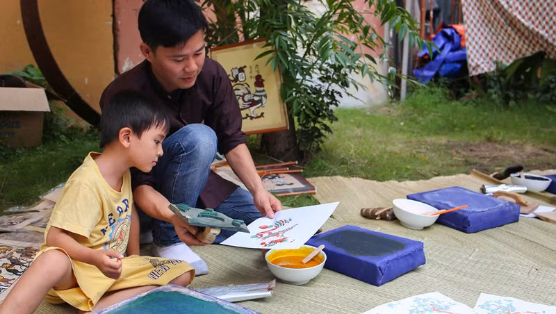 A kid is being instructed on how to make Dong Ho print at an event in Ho Chi Minh City (Image: Zing)