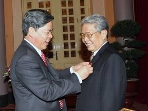 Nguyen Minh Quang presents the 50-year Party membership insignia to former President Tran Duc Luong.