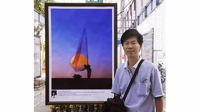 Photographer Dang Quang Vinh with one of his works. (Photo: NDO)