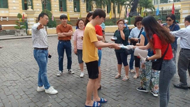 Tour guides presenting free masks to visitors. 