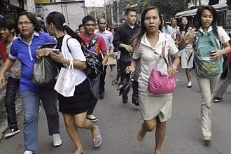 Workers and students run after they feel the magnitude 6.7 earthquake along a main street of Honkera, Cebu city, central