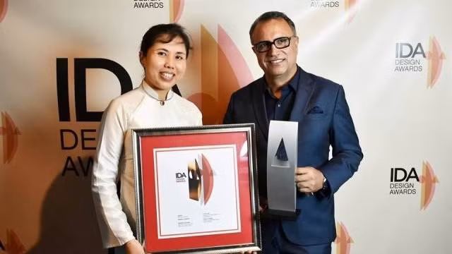 Hossein Farmani, chairman of the IDA (right), presents the certificate to painter Nguyen Thu Thuy (L)