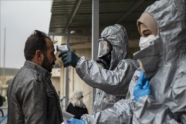  Medics check body temperature of passengers upon their arrival by bus in Syria's Kurdish area from Iraqi Kurdistan via the Semalka border crossing in Syria on March 1. (Photo: AFP/VNA)