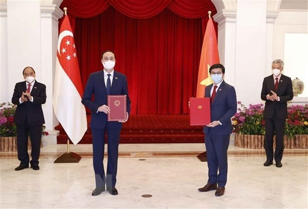 Vietnamese President Nguyen Xuan Phuc (first, left) and Singaporean Prime Minister Lee Hsien Loong (first, right) witness the exchange of a newly signed MoU between the Vietnam Fatherland Front and the People’s Association of Singapore on February 25 (Photo: VNA)