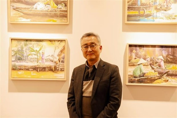 Kim Jai-min, a retired teacher in the Republic of Korea (RoK), stands next to his paintings on Vietnam. (Photo: VNA)