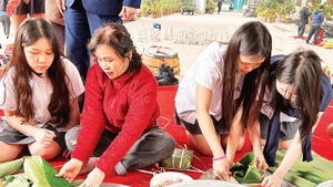 Students experience wrapping banh chung with members of the Intergenerational Self-Help Club in Khuong Dinh Ward (Ha Noi City).