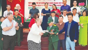 Representatives of Texas Tech University hand over documents to war veteran and wounded soldier Do Xuan Thuyen.