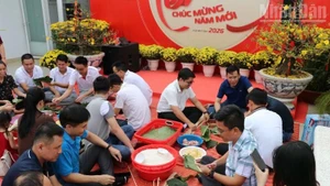 Many Vietnamese and Cambodian staff members of Metfone under the Viettel Military Industry and Telecoms Group (Viettel) take part in wrapping banh chung together during Tet. (Photo: HUY VU)
