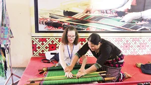 Artisan H’Binh introduces Ma brocade weaving techniques to foreign visitors at the cooperative. (Photo: nhandan.vn)