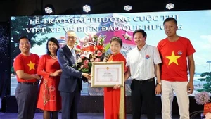 Vietnamese Ambassador to Germany Vu Quang Minh presents a certificate of merit and flowers to Bui Thi Thu Minh, head of the Vietnamese Liaison Committee in Europe "For Viet Nam's Seas and Islands", President of the Truong Sa Club in Germany. (Photo: VNA)