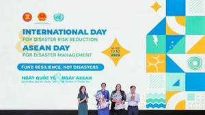 Deputy Minister of Agriculture and Environment Nguyen Hoang Hiep and Pauline Tamesis, UN Resident Coordinator in Viet Nam present flowers to welcome WHO and IOM as new members of the disaster risk reduction partnership. (Photo: VNA)