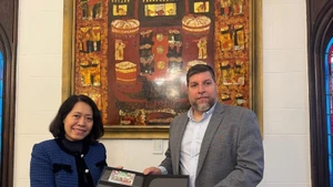 MP Victor Aldaya presents Ambassador Ngo Minh Nguyet with a set of stamps issued by Uruguay's National Post Office in December 2013, commemorating the 20th anniversary of Viet Nam-Uruguay diplomatic relations. (Photo: VNA)