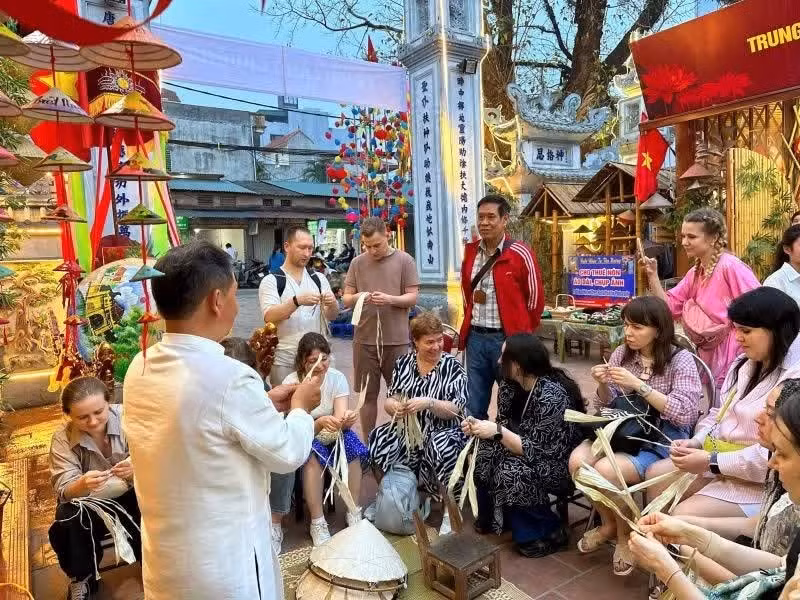 Artisan Le Van Tuy instructs foreign visitors on how to make traditional conical hats.