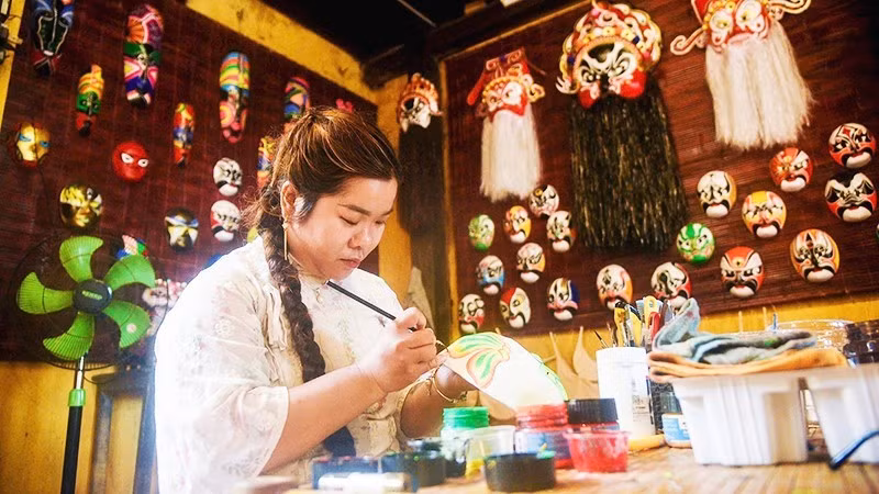 Huyen Trang paints masks at her family’s display and experiential space.