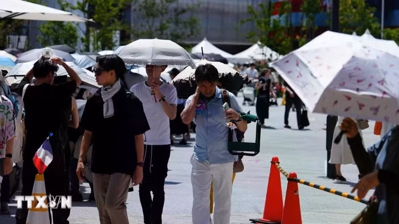 Pedestrians use umbrellas to shield themselves from the sun in Osaka, Japan. (Photo: Xinhua/VNA)