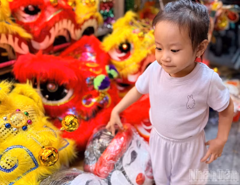 Children accompanied by their parents on a stroll along Hang Ma Street are drawn to lion heads and paper masks.